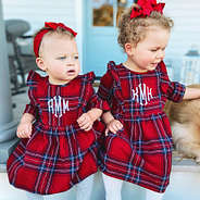 sisters wearing matching holiday plaid dresses