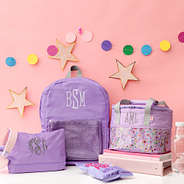 Kids lavender toiletry bag with lunch box and backpack on pink background